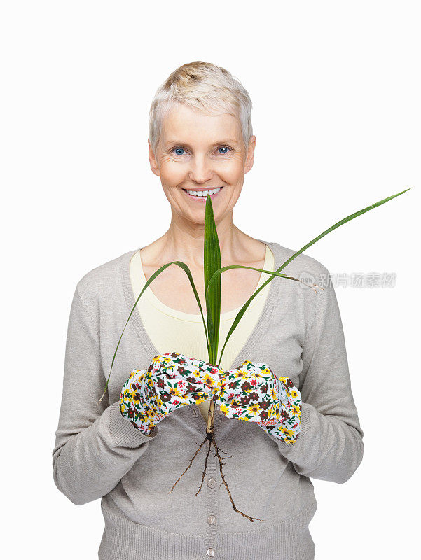 快乐的老女园丁抱着一株白嫩的植物