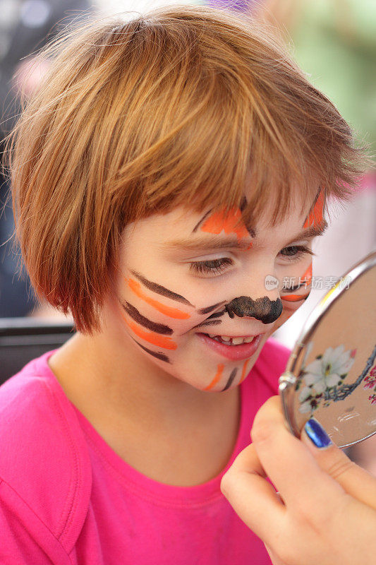 小女孩在镜子里看着她画过的老虎脸