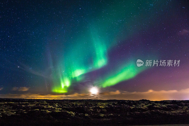 北极光和月亮落在冰岛的熔岩田上