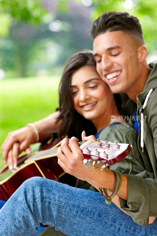 一对欢快的年轻夫妇在公园里弹吉他