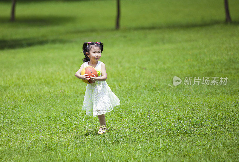 可爱的亚洲女孩在户外抱着球