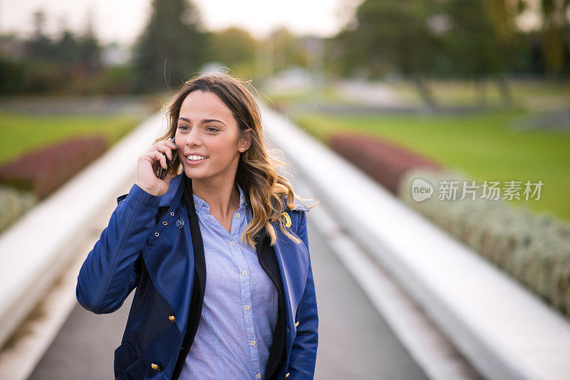 谈笑风生的女商人一边聊着智能手机一边看着