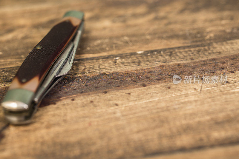 一把多功能或袖珍小刀放在质朴的木桌上。