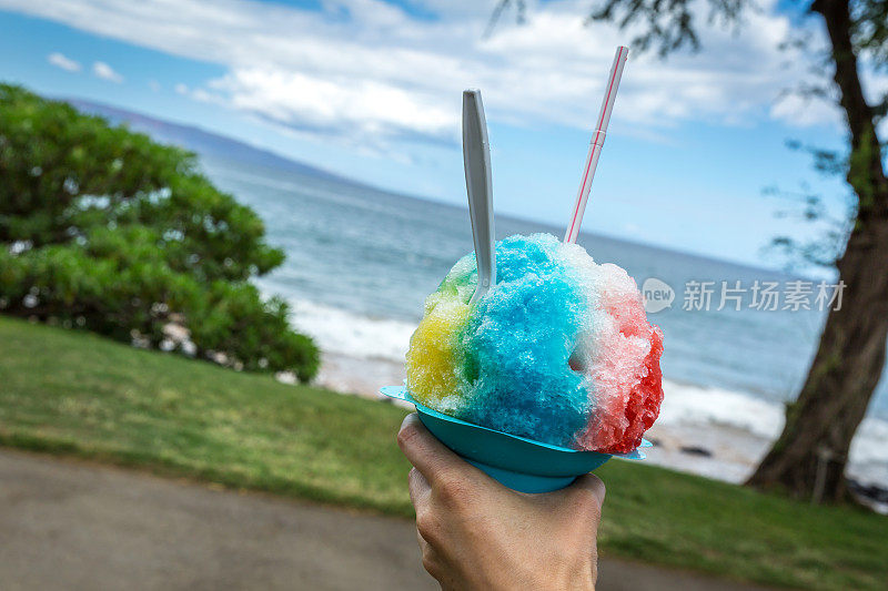 热带海滩上的人手握着夏威夷刨冰