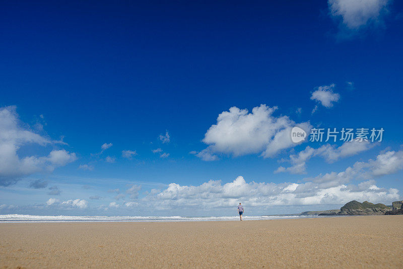 一个人走在水门湾海滩在一个美好的日子。