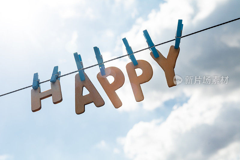 挂在晾衣绳上的木制字母写着快乐