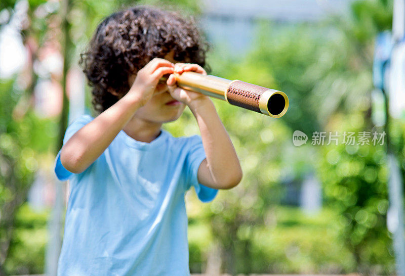 小男孩拿着望远镜在公园里