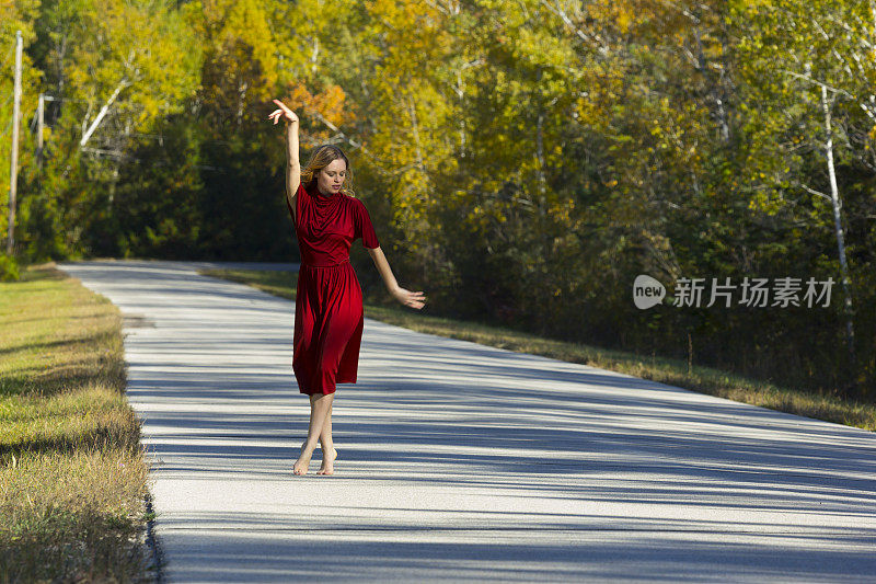 时尚的女人赤脚跳舞在红色的裙子，秋天风景