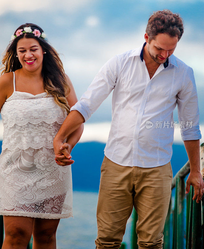 在阳光明媚的日子里，一对年轻激情的新婚夫妇在海滩上的码头上