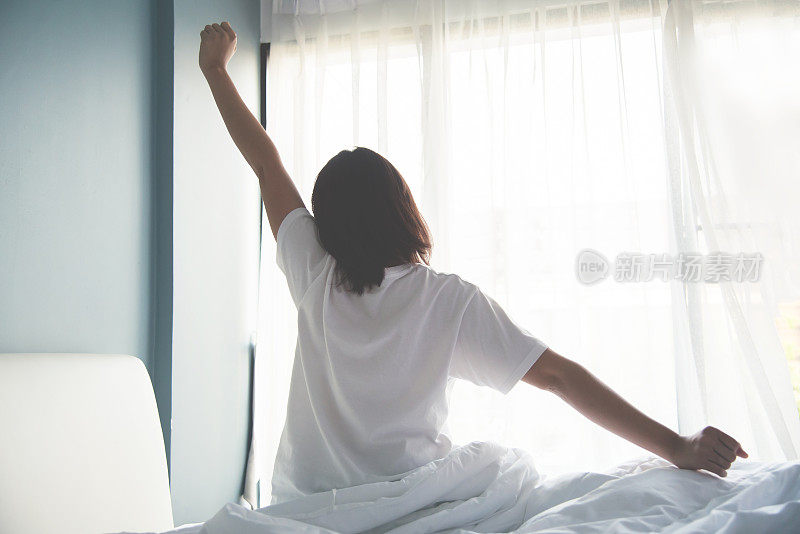 早上醒来的亚洲女人。伸出手臂。