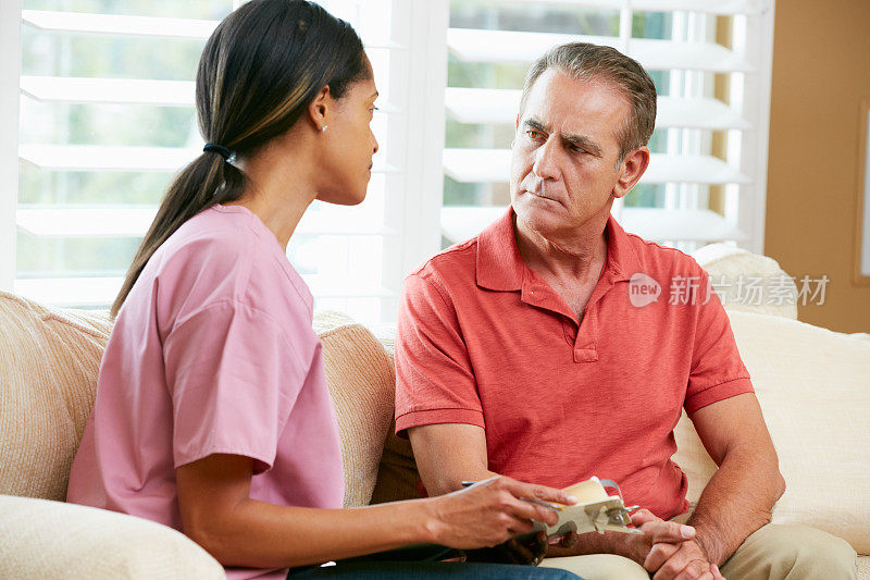护士在家访中与老年男性病人讨论病历