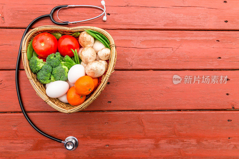 蔬菜和水果放在一个带有听筒的心形篮子里