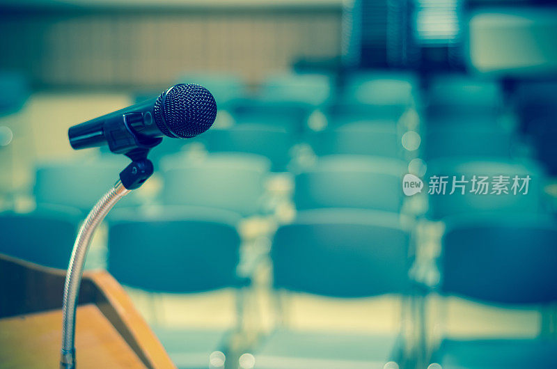演讲台上的麦克风上方抽象模糊的照片是会议厅或会议室的背景