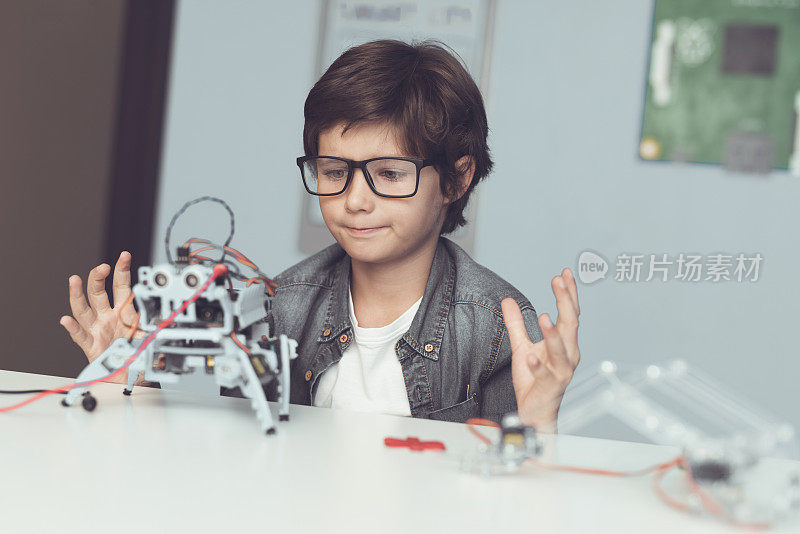 一个戴眼镜的小呆子正抱着一个机器人。他热情地看着自己的创作