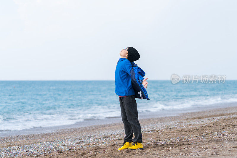 快乐的男孩在一个冬日的海滩上散步