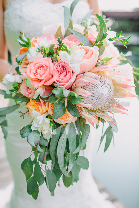 新娘手持一束花束，花束上有proteus和玫瑰。结婚的那一天