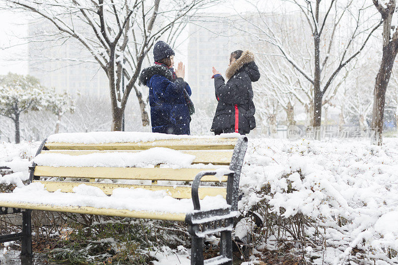 女性朋友穿着暖和的衣服，在雪地里画像