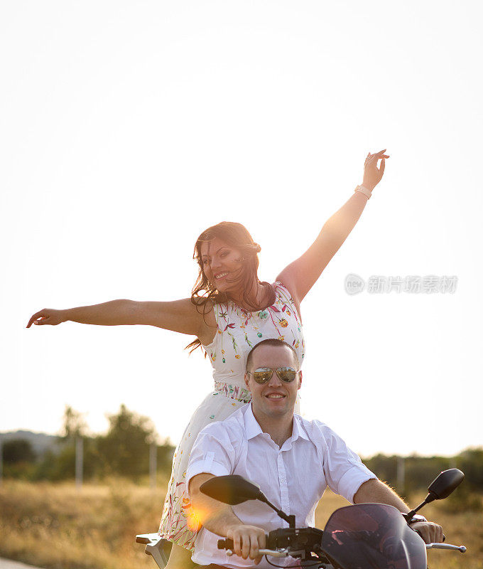 快乐的年轻夫妇在摩托车上享受公路旅行