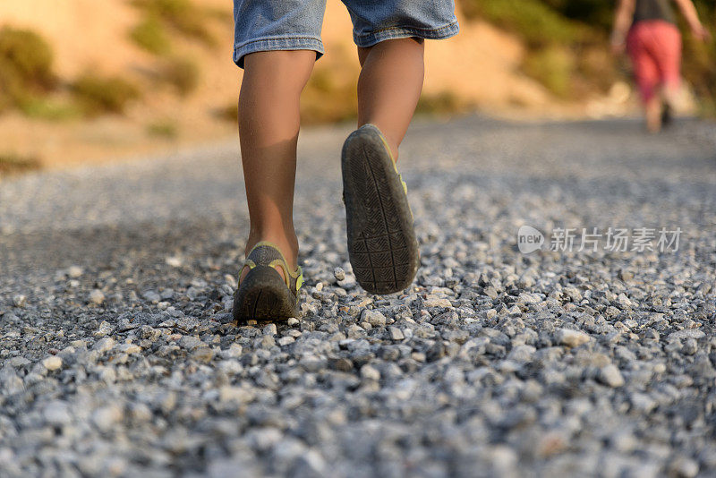 一个小孩走在砾石小路上