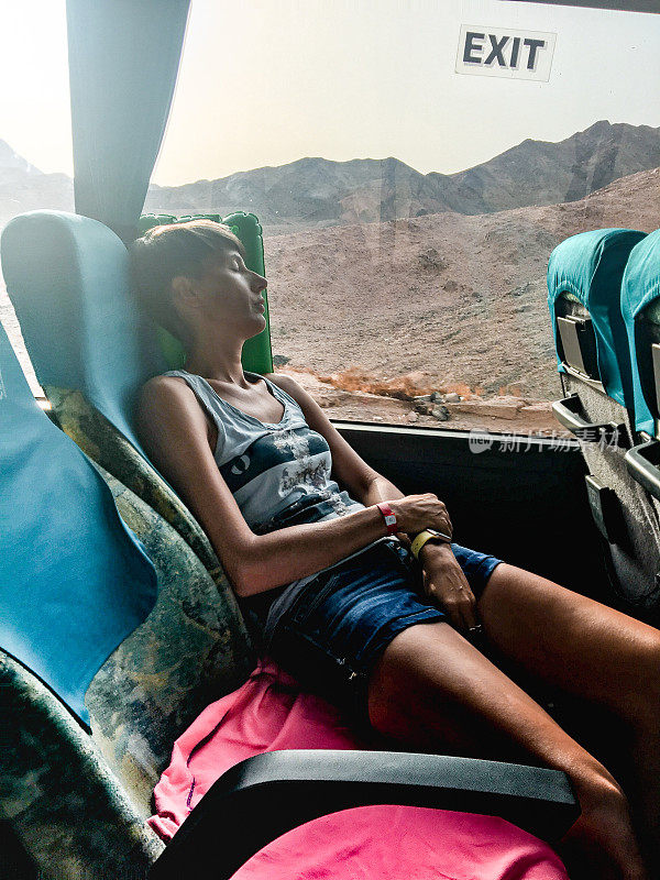 中年妇女在穿越沙漠时睡在公交车上