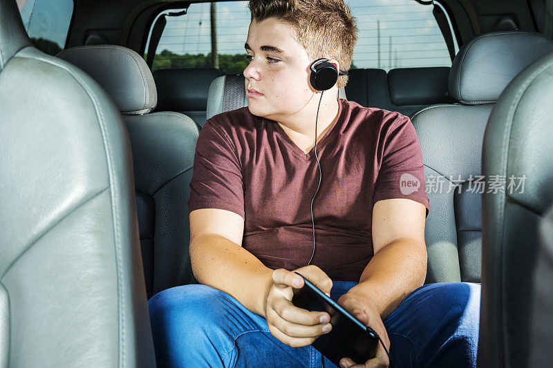 十几岁的男孩在SUV的后座上听音乐