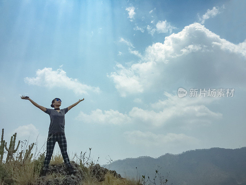 快乐的年轻女子喜欢山里的新鲜空气。