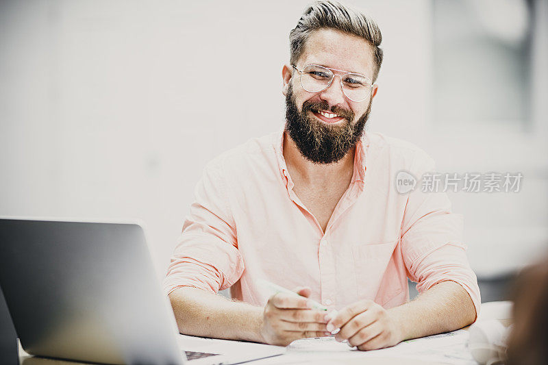 微笑的男性建筑师使用笔记本电脑和手机