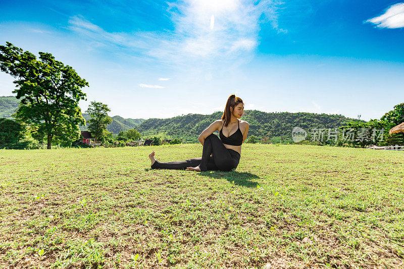 亚洲妇女练习瑜伽向前弯曲，Sage扭转C姿势或Marichyasana姿势伸展运动肌肉与瑜伽冥想放松和刷新健康在绿色草地上感觉幸福和舒适