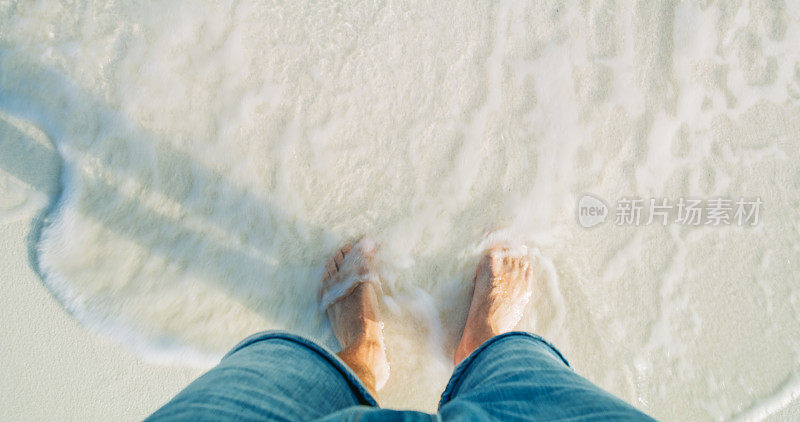 人的脚站在马尔代夫的海滩上