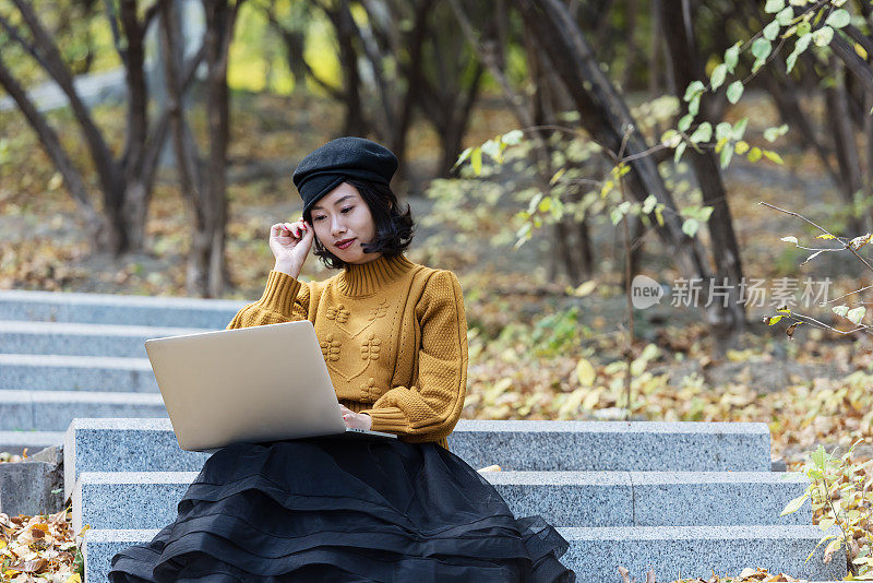 一个亚洲女孩在公园里操作笔记本电脑