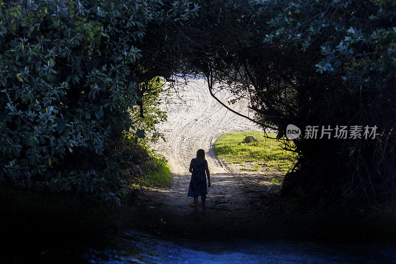 一个女人走在阴森森的乡间小路上的剪影