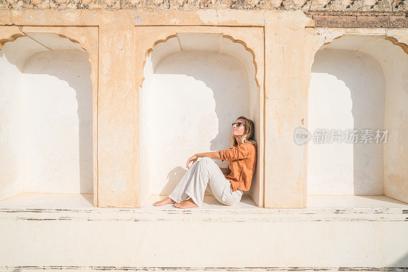 年轻女子在印度参观寺庙，坐在窗户上思考建筑。人们旅游发现亚洲的概念。