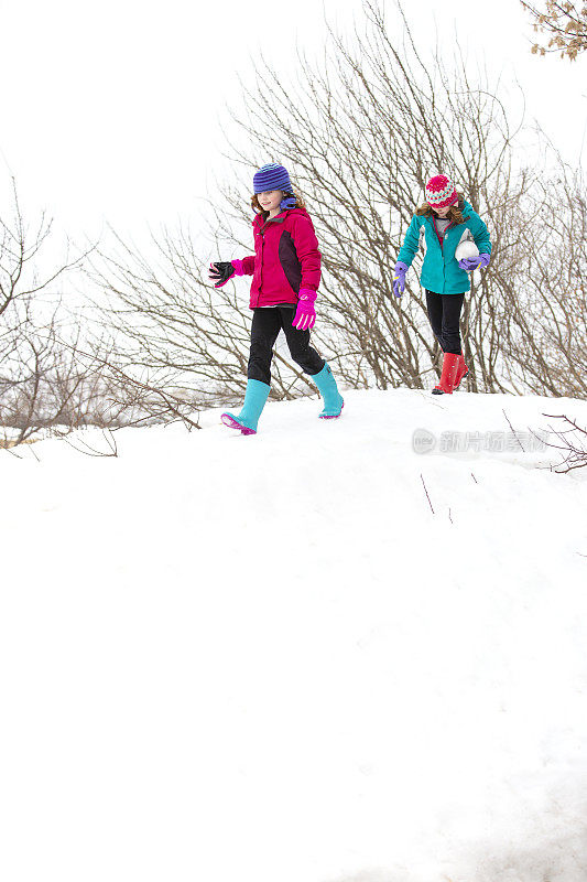 两个小女孩在雪堆上行走