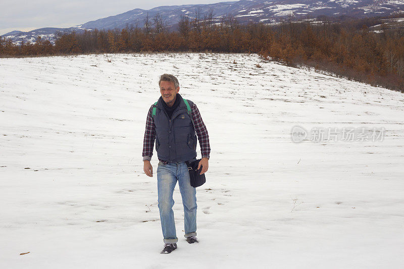 美丽快乐的成年男子徒步旅行户外在雪地在冬末