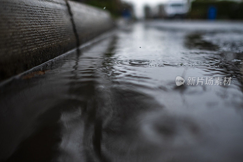 在一个阴沉的冬日，雨点落在路边的水坑里。