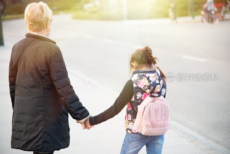 爷爷奶奶的爱。祖母和孙女手牵着手在公园里散步
