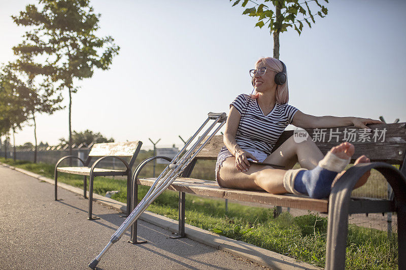 一个断了腿的年轻女子在一个阳光明媚的夏日里享受