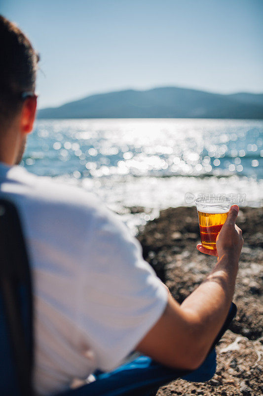 在海滩上喝啤酒的男人