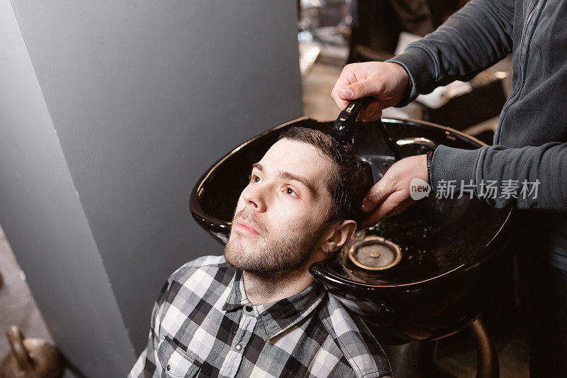 师傅在理发店里给顾客洗头，美发师为年轻人做发型。