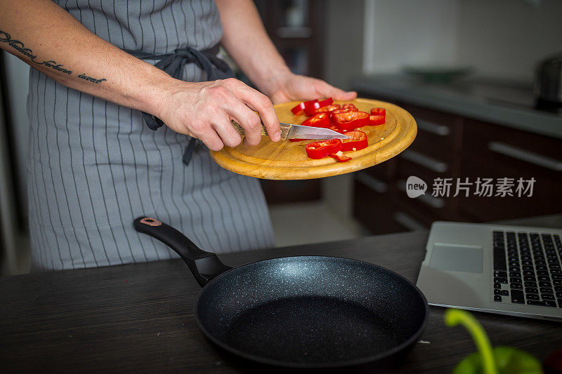 男人在厨房的桌子上切新鲜的春天蔬菜，特写。准备家庭食物，家庭厨房内部。