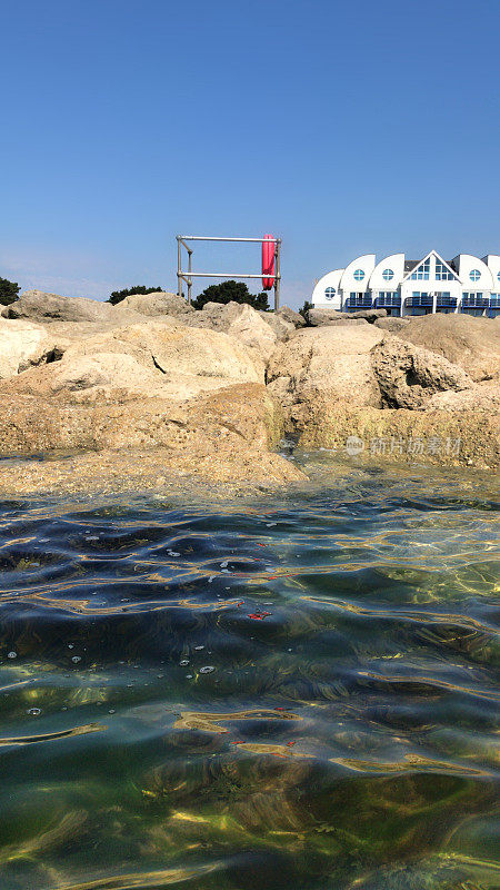 从海上看内陆的海边海滩岩石海防的图像，在英国多塞特郡普尔海滩的沙滩上，有海岸的景色和平静的大海和蓝天