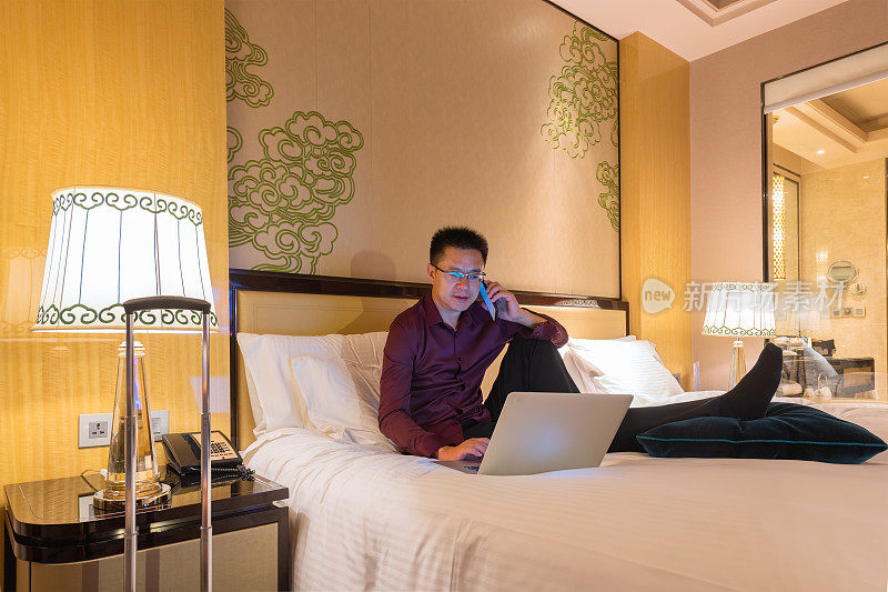 一个商人在酒店房间的床上用笔记本电脑工作