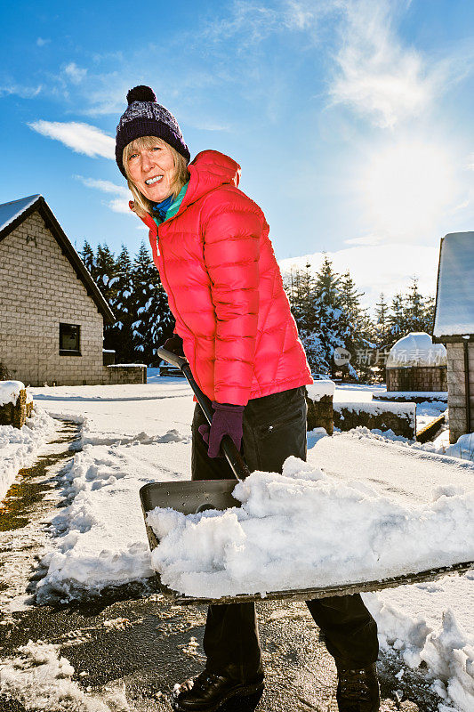 老妇人正在用雪铲清理前院的积雪