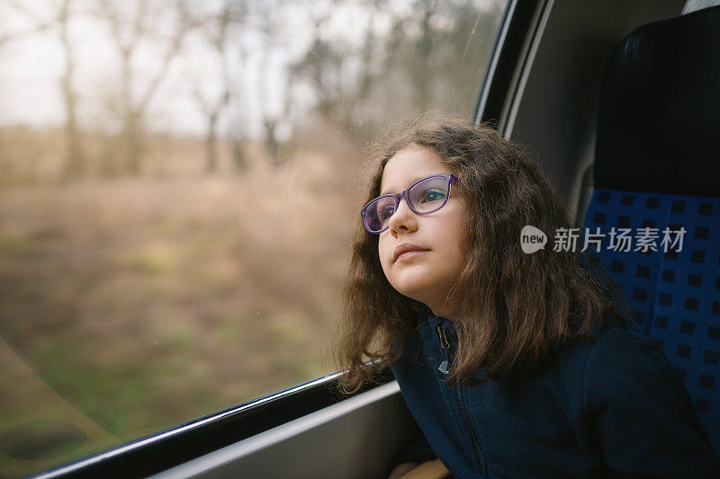 可爱的小女孩透过火车窗户欣赏美丽的风景