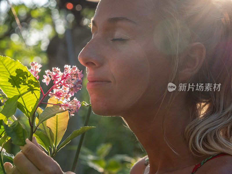 年轻女子在热带花园里闻着花香