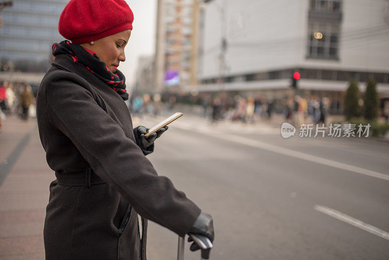 漂亮的肤色女人使用手机应用程序得到一个出租车