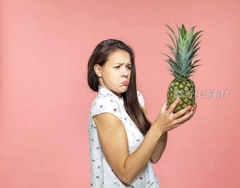 年轻女子做了一个不高兴的表情，拿着菠萝