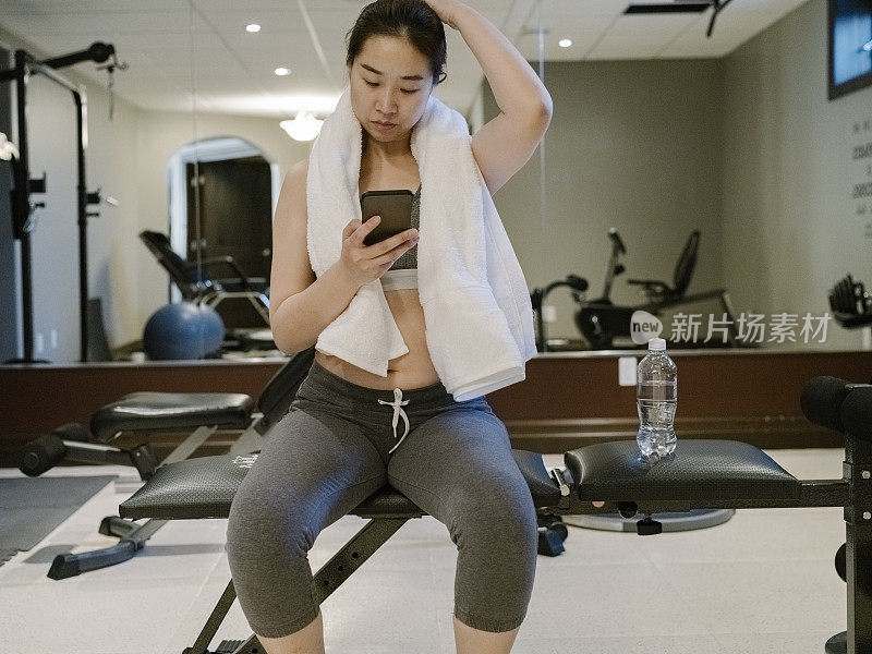 亚洲女性在家庭健身房使用手机