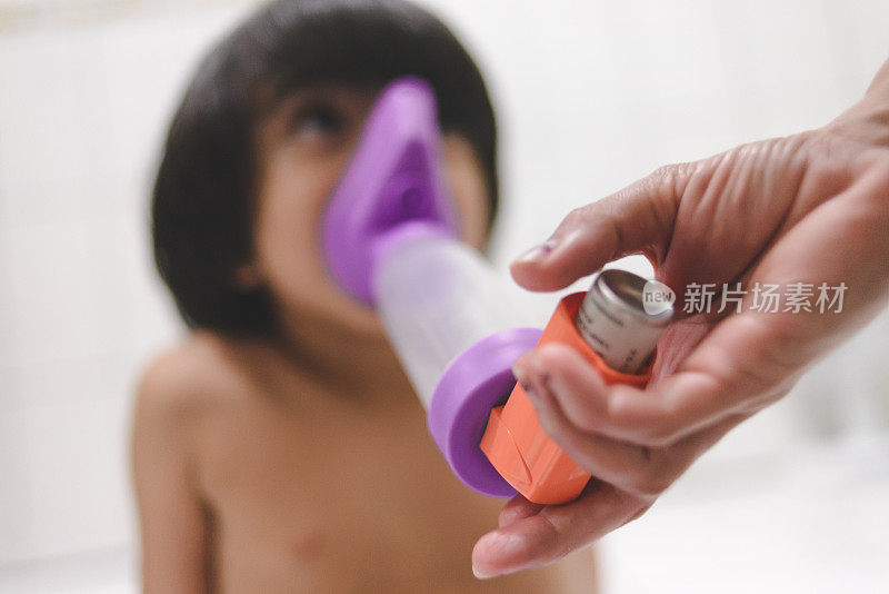 小男孩使用哮喘吸入器，有隔膜和吸嘴