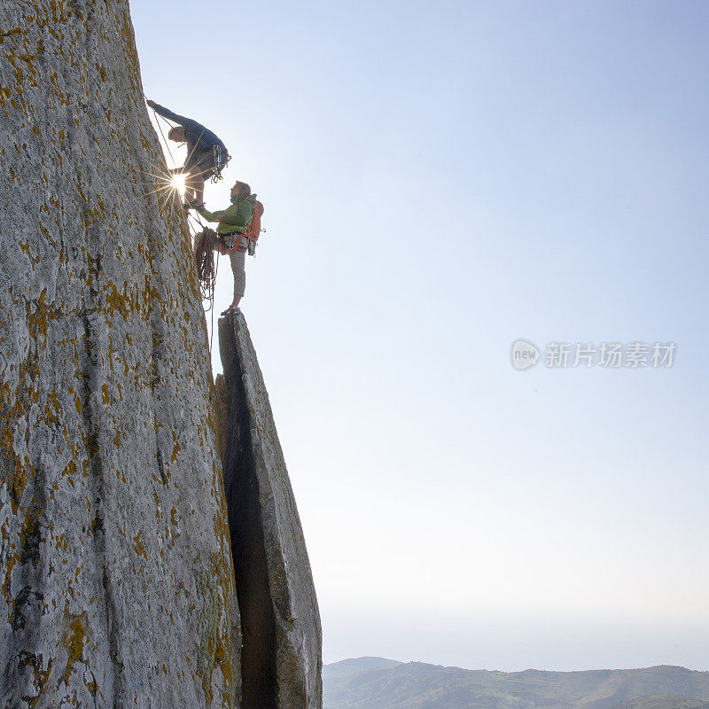 登山者在日出时攀登岩面